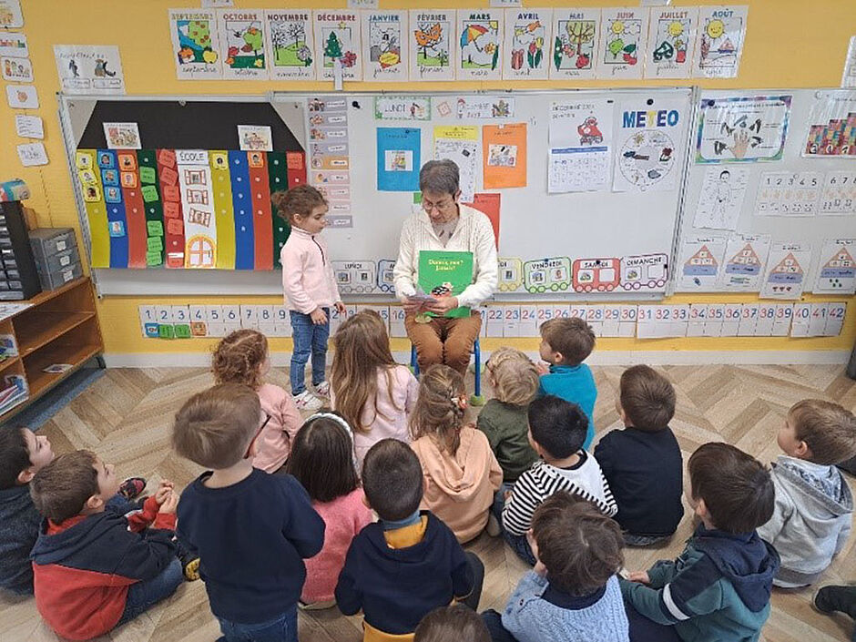 photo dans la classe pendant l'activité, une personne lit une histoire aux enfants et montre les pages du livre